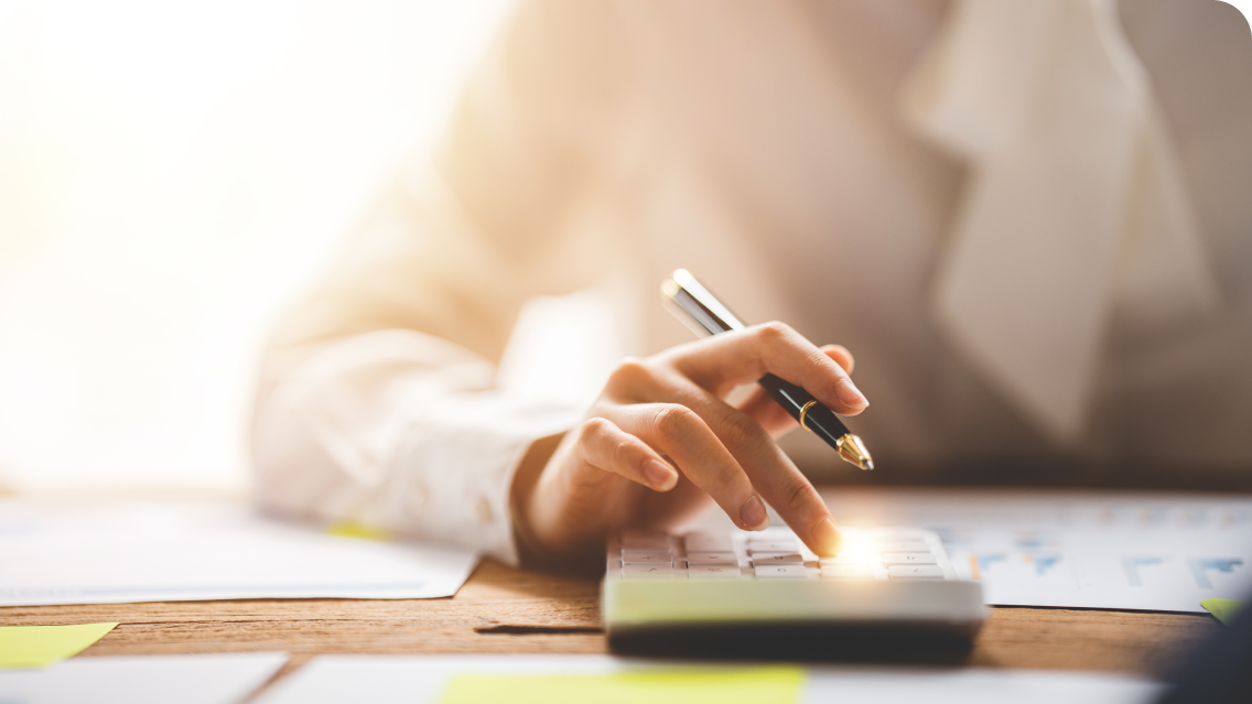 Person in white shirt using calculator at desk